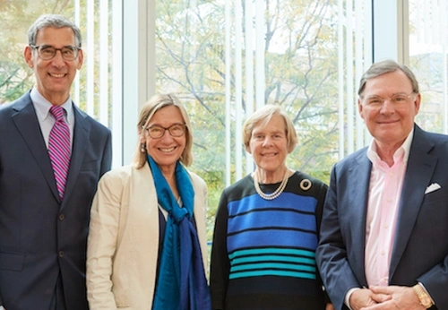 Michael Golden, Pam Grossman, Suzanne McGraw, and Harold McGraw III posing for photo in front of a window.