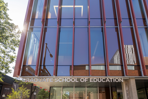 The sun flares on the front of the GSE building with the Graduate School of Education sign clearly visible