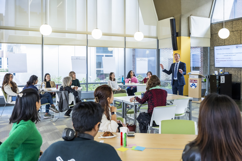 A person giving a presentation in front of a group of people in a classroom