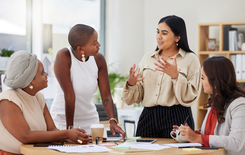 4 professional women having a conservation around a table.