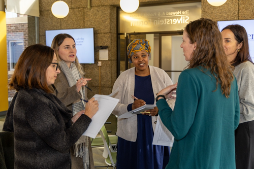 Five women standing in a circle having a conversation