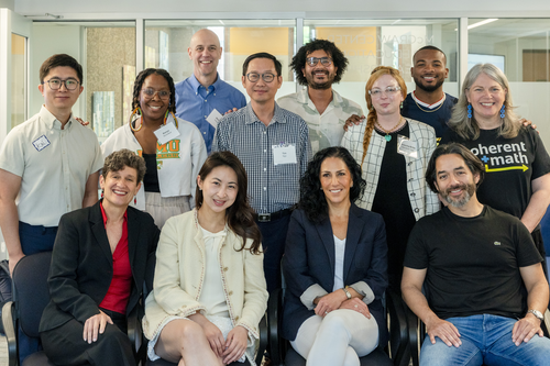 12 people—including the dean, Jenny Zapf, Roger Osorio, and the alumni fellowship founder—pose in a classroom
