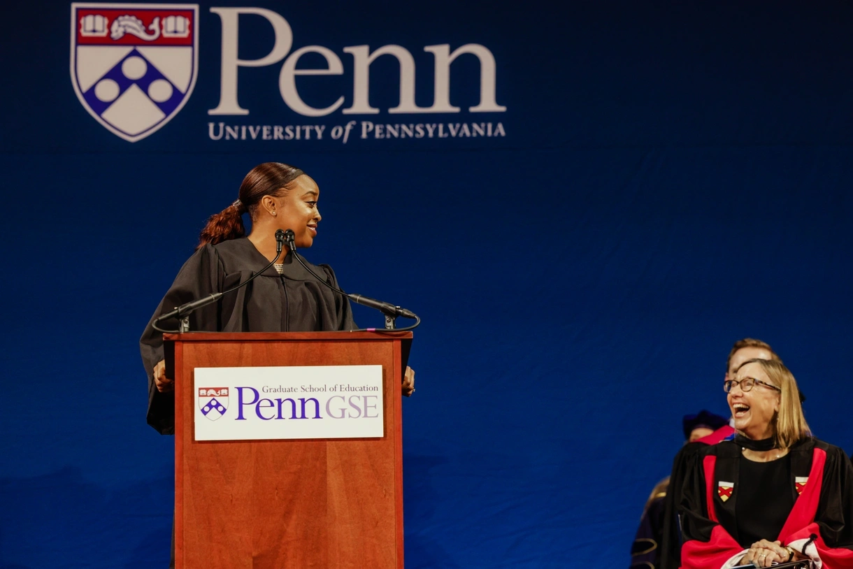 Abbott Elementary&nbsp;creator&nbsp;Quinta Brunson stands at a podium sharing a laugh with Penn GSE Dean Pam Grossman, seated to her right.