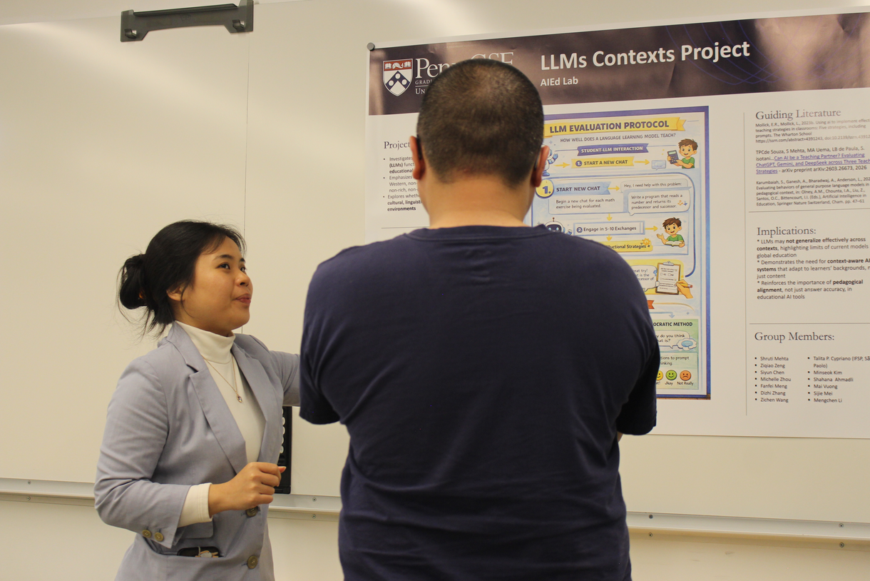 A person explains their displayed poster to another person whose back is to the camera.