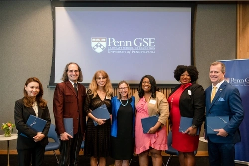 Dean Grossman (center) in front of a projector with a PennGSE screen and along side this year's recipients of the Education Alumni Awards