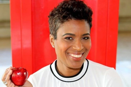 Headshot of Jennifer Stimpson holding an apple in front of a red background