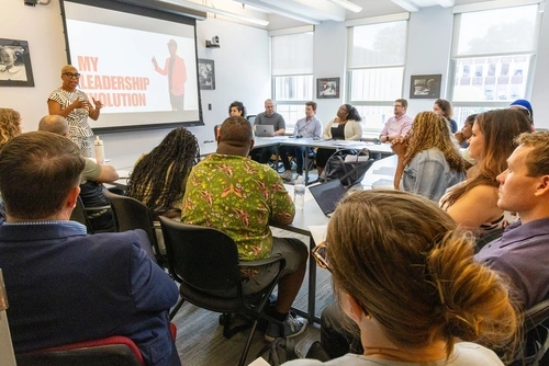 A School Leadership program (SLP) alum gives a talk to a packed classroom during the SLP 25th anniversary event