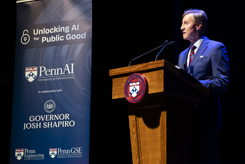 President Larry Jamison speaks a podium with a Penn seal on it next to a banner that reads "Unlocking AI for Public Good"