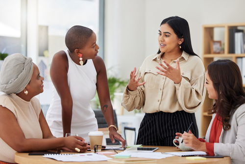 4 professional women having a conservation around a table.