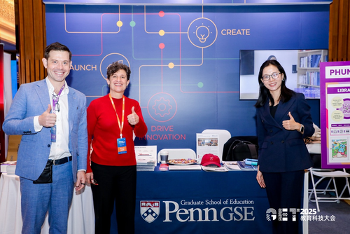 Three people stand in front of a table with a Penn GSE tablecloth on it giving thumbs up.