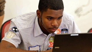 A student sits and works at a laptop computer. 