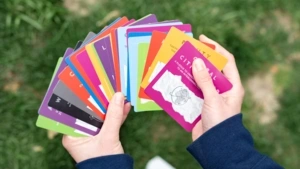 A set of colorful cards with words and images on them fanned out in a pair of hands.