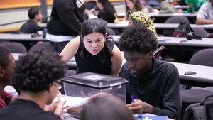 A Penn GSE doctoral candidate and a group of Philadelphia high school students examine a spider in a terrarium