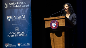 Dean Strunk speaks at a podium with a Penn seal on its front and next to a banner that reads "Unlocking AI for Public Good" with logos from PennAI, Governor Shapiro's office, Penn GSE, and Penn Engineering on it. 