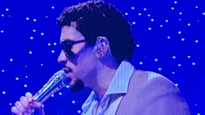 Puerto Rican music star Bad Bunny sings into a microphone on stage.