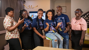 Six Ghanaian students stand together in a row smiling and laughing amongst each other.